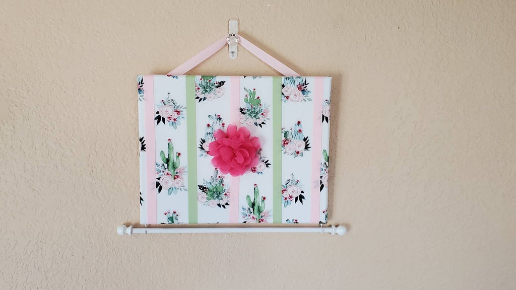 Cactus Hair Bow Holder with pink flowers hanging on stucco wall 